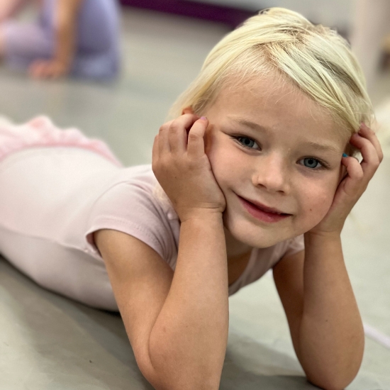 Young ballet dancer smiling on the floor during warm up