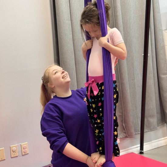 Miss Mystaya assisting a young dancer in the arial silks